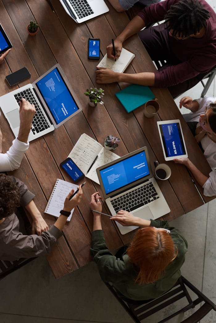 services-04 A diverse group of professionals brainstorming with laptops and notepads in a modern office.